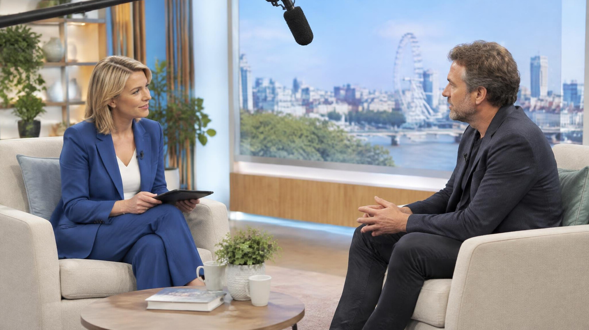 Presenter interviewing a guest on a studio set with microphones